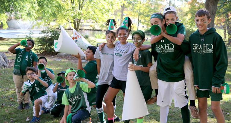 Chase Collegiate students pose together outside with megaphones and green accessories as they get into school spirit.